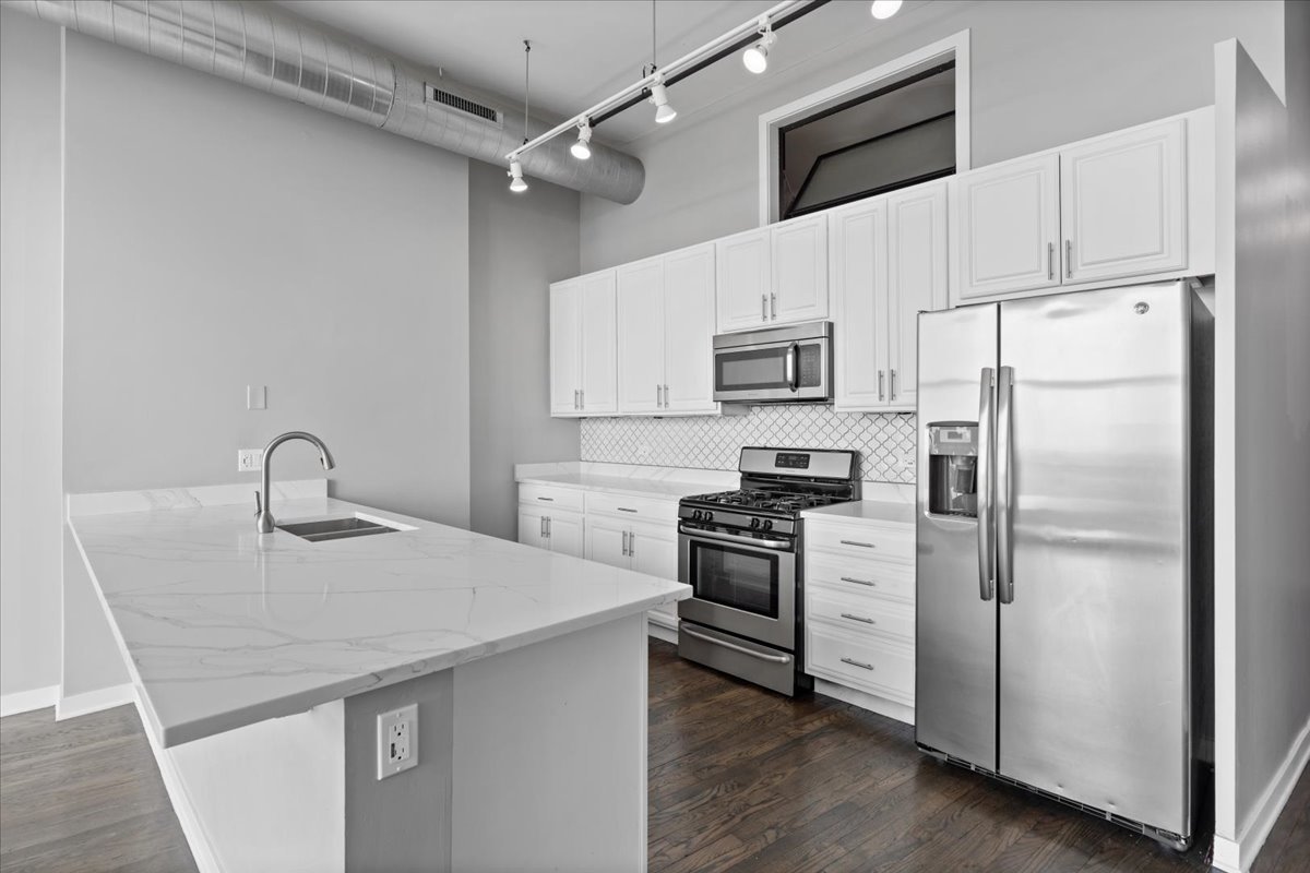 1224 West Van Buren Street, Unit 809 Chicago, IL 60607 - Photo 6 of 25 a kitchen with kitchen island a counter top space a sink appliances and cabinets