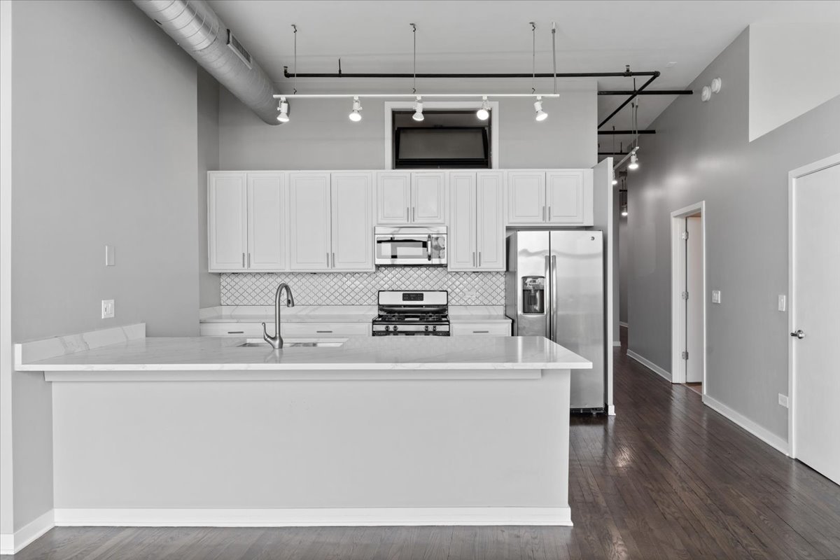 1224 West Van Buren Street, Unit 809 Chicago, IL 60607 - Photo 7 of 25 a kitchen with stainless steel appliances granite countertop a sink and a refrigerator