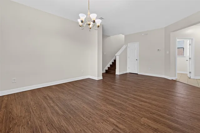 a view of empty room with wooden floor and chandelier