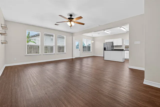 a view of an empty room with a kitchen and wooden floor