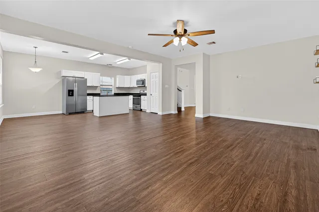 a view of empty room with wooden floor and ceiling fan