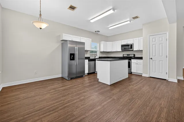 a kitchen with stainless steel appliances granite countertop a wooden floors a stove and a refrigerator