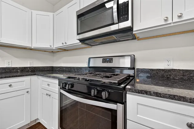 a kitchen with stainless steel appliances granite countertop white cabinets and a stove top oven