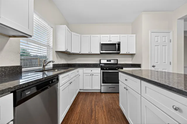 a kitchen with granite countertop white cabinets and stainless steel appliances
