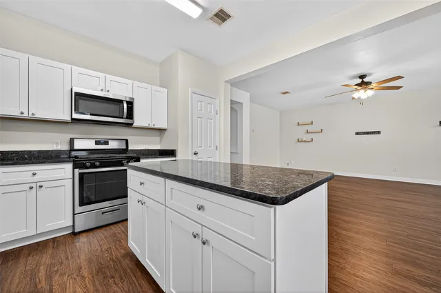 a kitchen with granite countertop a sink stainless steel appliances and white cabinets