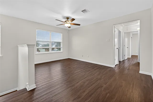 a view of an empty room with a window and wooden floor
