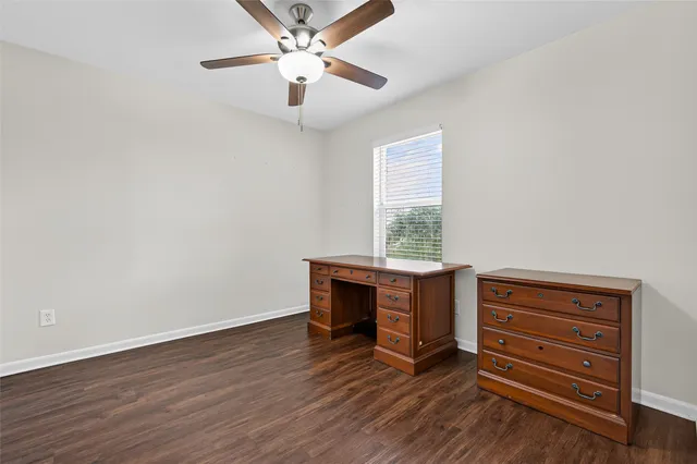 an empty room with wooden floor a ceiling fan and windows