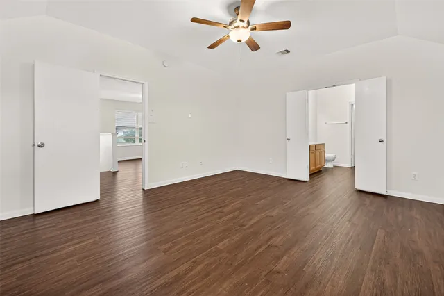 an empty room with wooden floor closet and windows