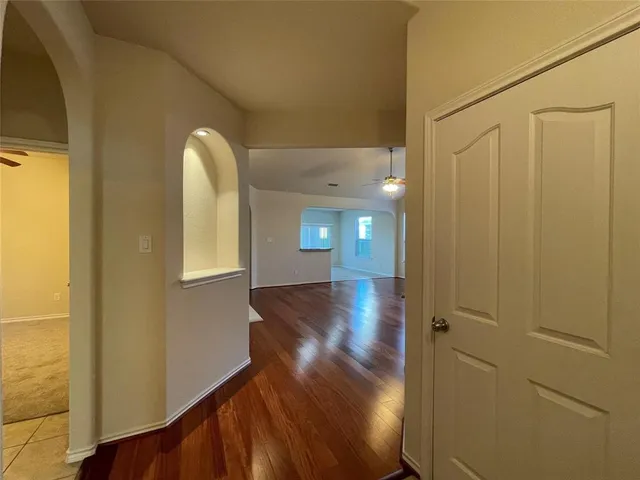 a view of a hallway with wooden floor and a bathroom