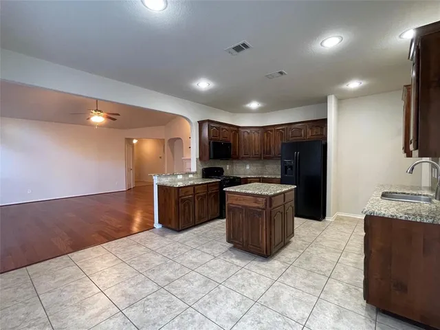 a large kitchen with stainless steel appliances kitchen island granite countertop a large counter top and a stove