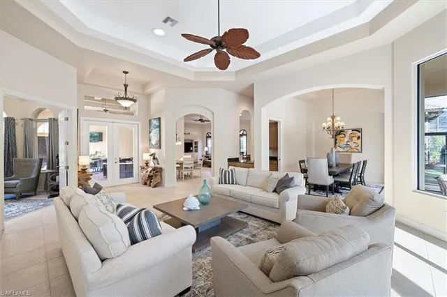 a living room with furniture a chandelier fan and a large window