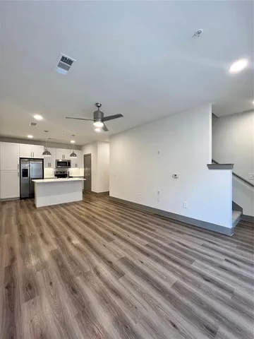 a view of kitchen and empty room with wooden floor