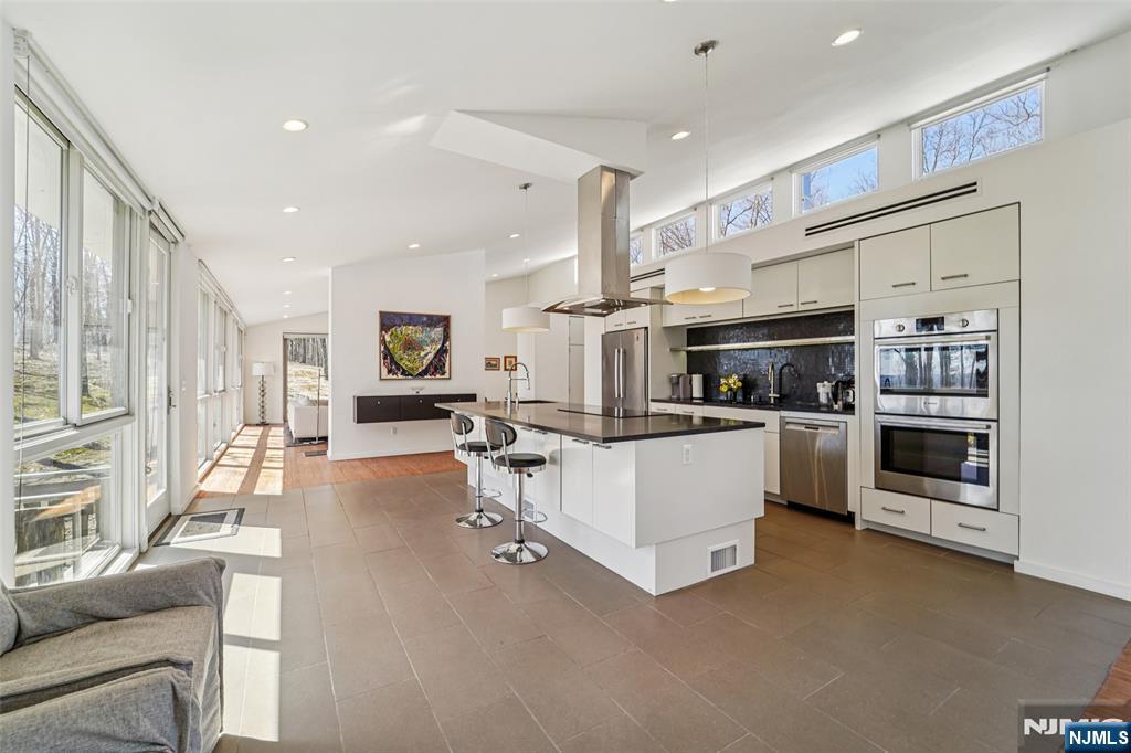 71 Sally Harden Road Sussex, NJ 07461 - Photo 14 of 33 a kitchen with stainless steel appliances kitchen island granite countertop a refrigerator oven stove a dining table and chairs with wooden floor