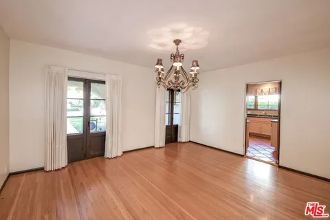 a view of a room with wooden floor potted plants and a chandelier