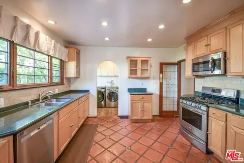 a kitchen with stainless steel appliances granite countertop a stove a sink and a microwave