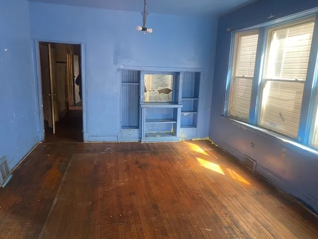 a view of an empty room with window and wooden floor
