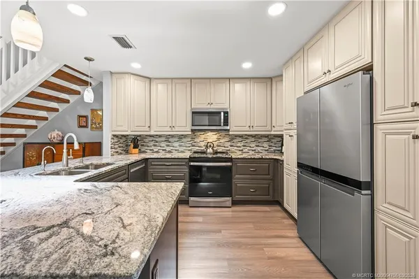 a kitchen with granite countertop a refrigerator and a sink