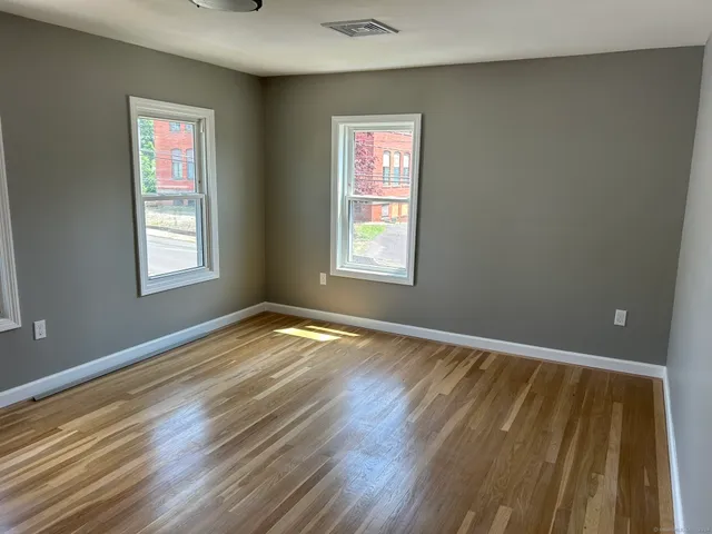 a view of an empty room with wooden floor and window