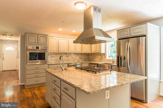 a kitchen with kitchen island granite countertop a sink appliances cabinets and furniture