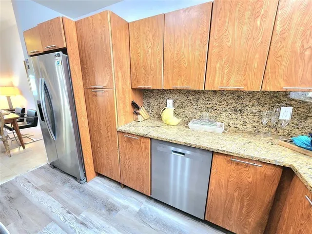 a kitchen with stainless steel appliances granite countertop a refrigerator a sink and a stove with wooden floor