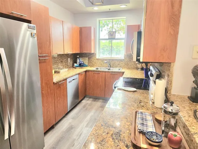 a kitchen with stainless steel appliances granite countertop a refrigerator sink and stove
