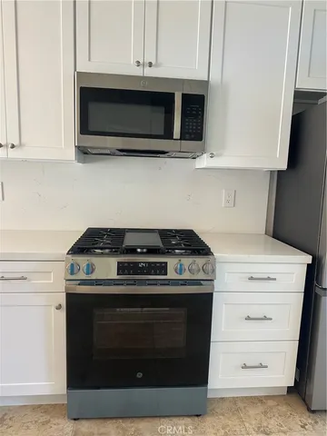 a view of a kitchen with white cabinets and a window