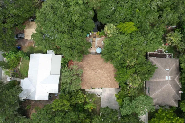 an aerial view of residential house with outdoor space and trees all around