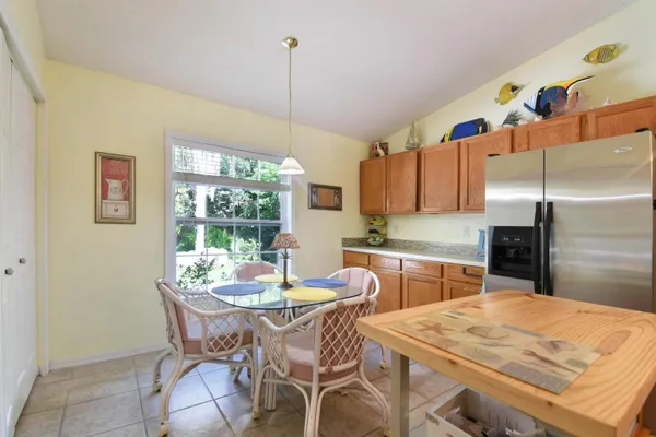 a kitchen with stainless steel appliances kitchen island granite countertop a dining table chairs and a refrigerator