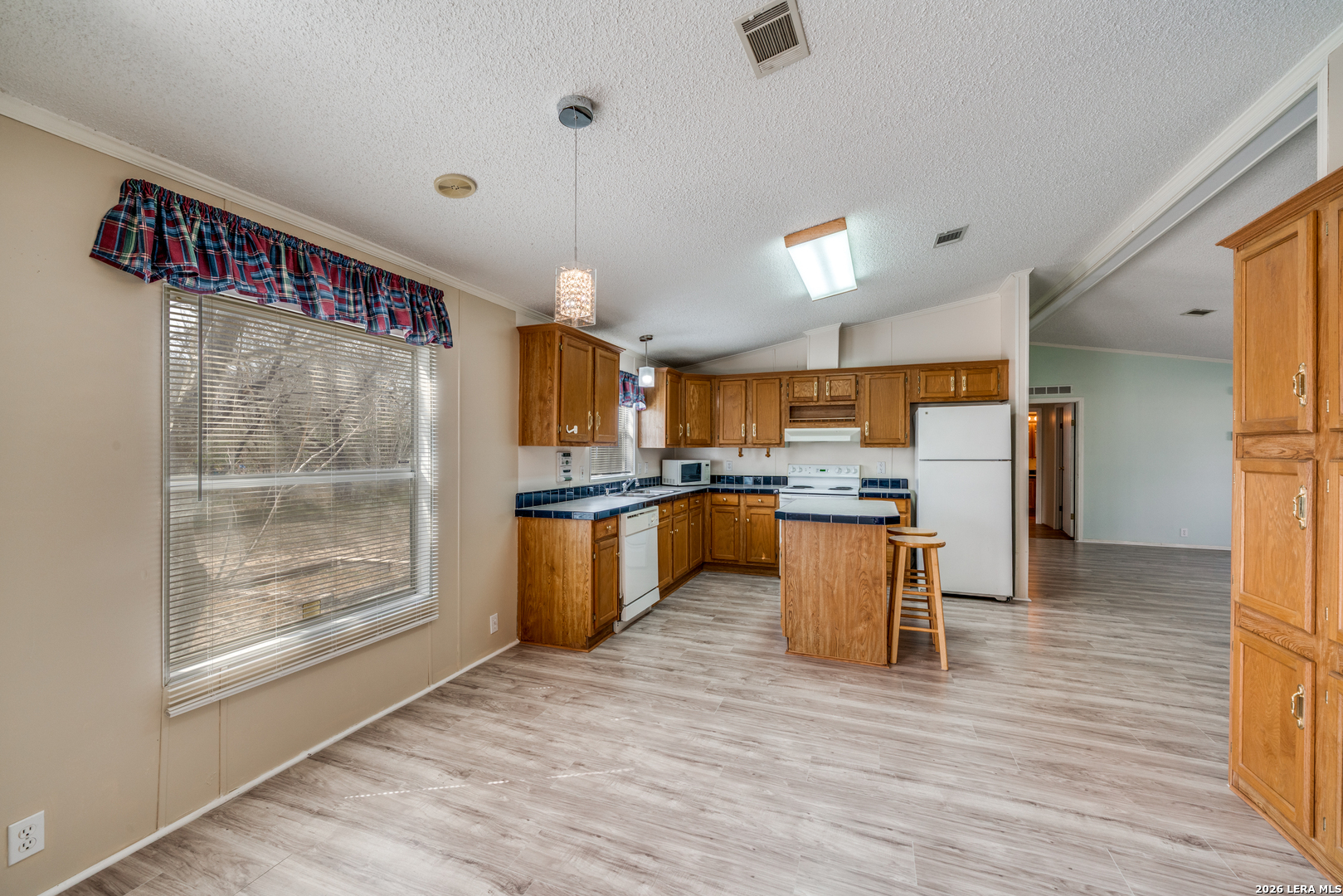 14975 Flatten Road San Antonio, TX 78223 - Photo 11 of 28 a kitchen with stainless steel appliances kitchen island granite countertop a refrigerator a sink a stove and a wooden floors