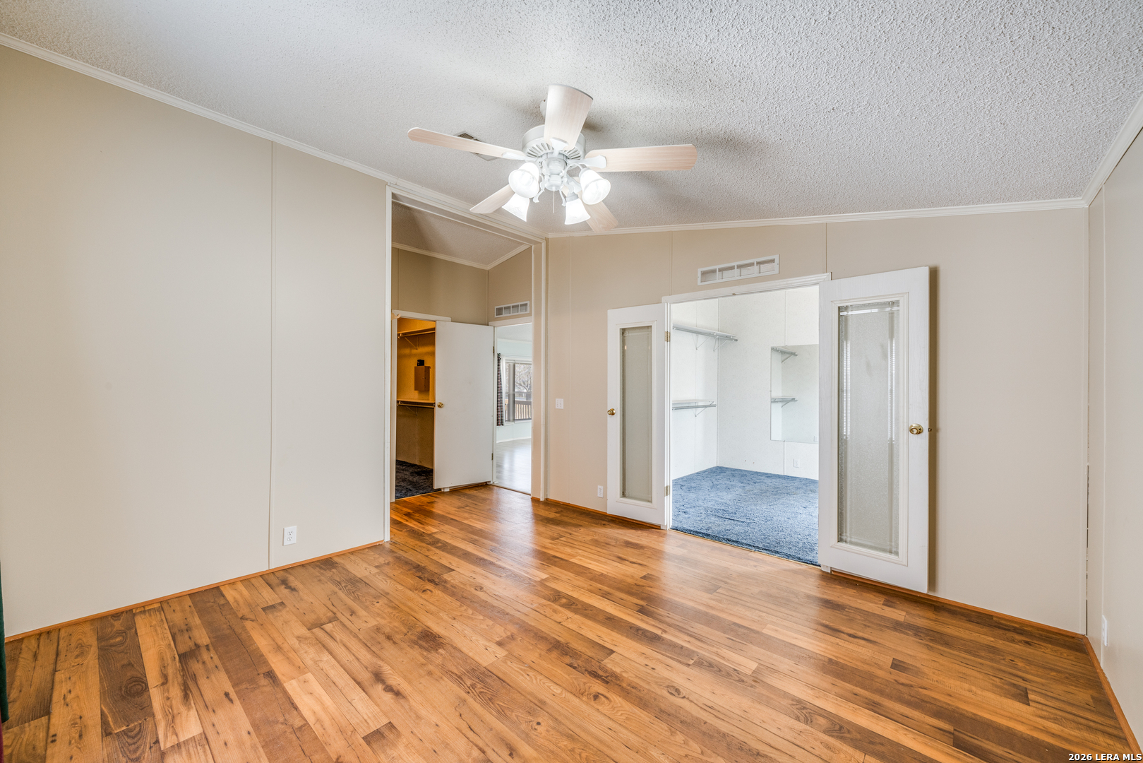 14975 Flatten Road San Antonio, TX 78223 - Photo 16 of 28 a view of an empty room with wooden floor and a ceiling fan