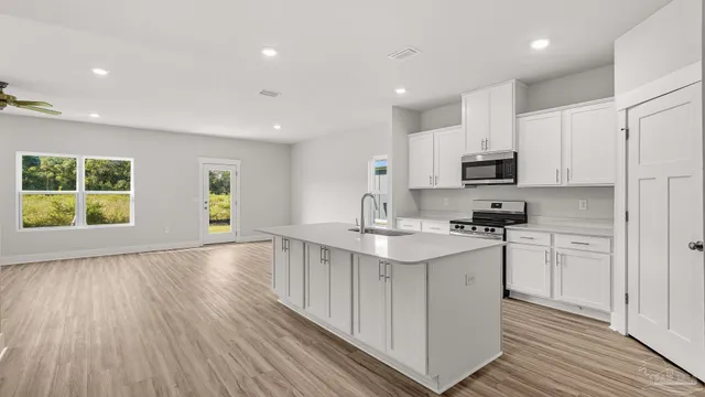 a kitchen with a sink dishwasher stove and white cabinets with wooden floor