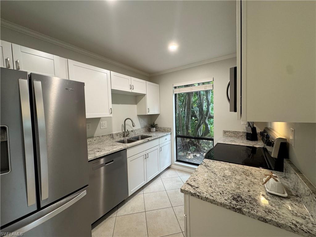 1281 Solana Road Naples, FL 34103 - Photo 13 of 31 Kitchen featuring ornamental molding, light tile patterned floors, appliances with stainless steel finishes, white cabinets, and a sink