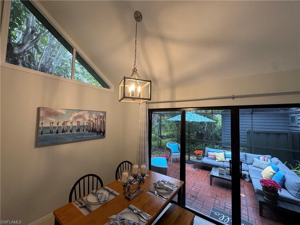 1281 Solana Road Naples, FL 34103 - Photo 14 of 31 Dining room featuring an inviting chandelier, brick floor, a wealth of natural light, and vaulted ceiling