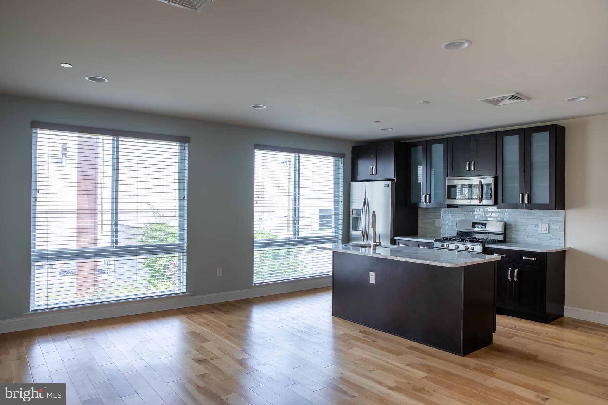 a kitchen with stainless steel appliances granite countertop a stove a sink a refrigerator and wooden floor