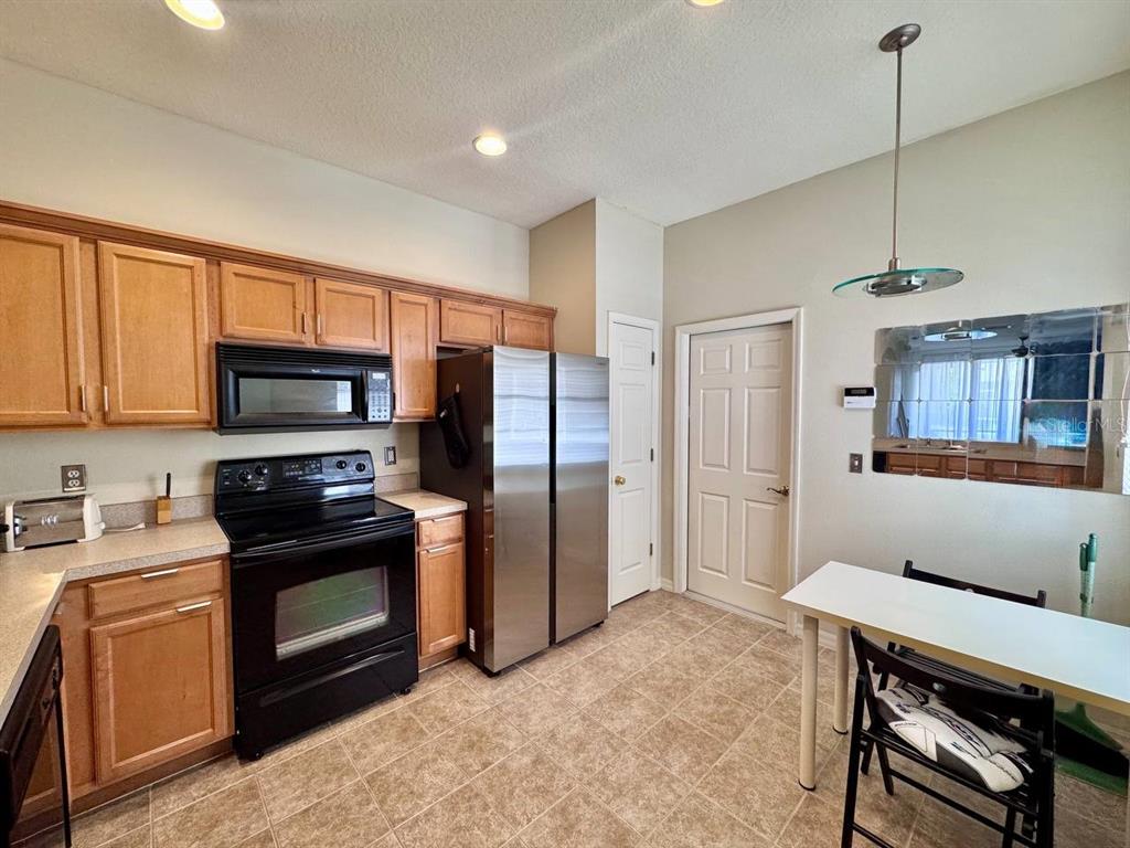 10035 Tranquility Way Tampa, FL 33625 - Photo 10 of 28 a kitchen with stainless steel appliances granite countertop a stove a refrigerator and a sink with wooden cabinets