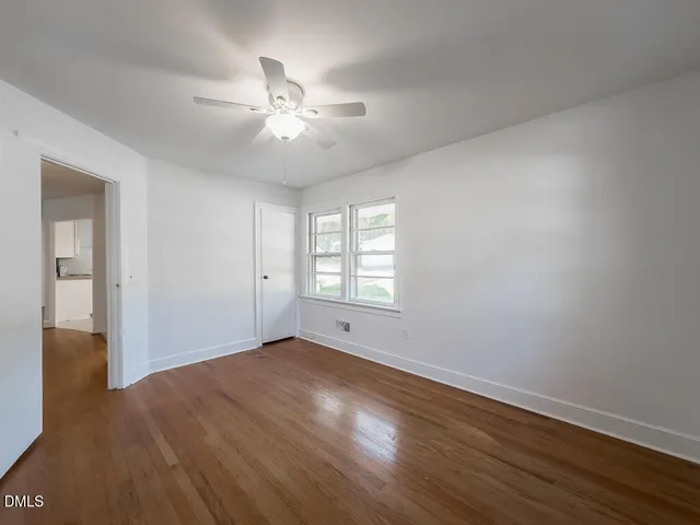 a view of an empty room with wooden floor and a window