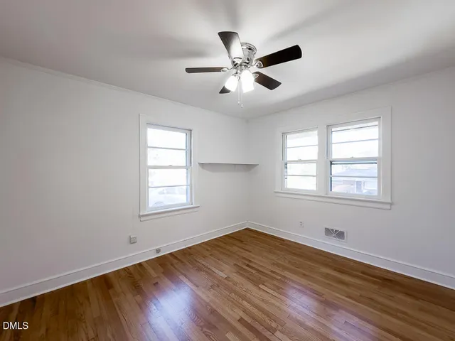 a view of empty room with wooden floor and fan