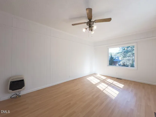 an empty room with wooden floor fan and windows