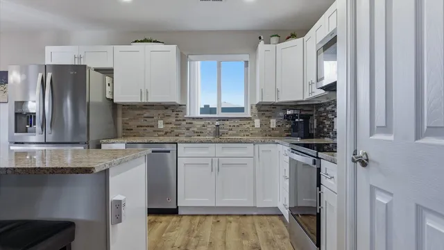 a kitchen with stainless steel appliances granite countertop a refrigerator sink and stove