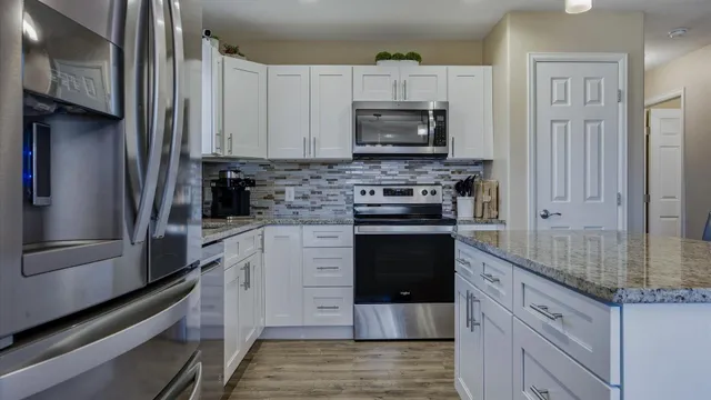 a kitchen with stainless steel appliances granite countertop a stove microwave and a refrigerator