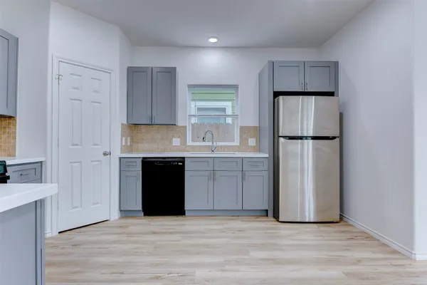 a kitchen with kitchen island granite countertop a refrigerator a sink and wooden floors