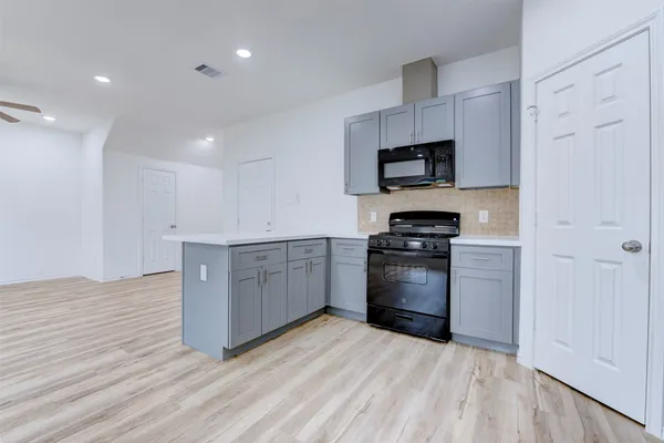 a kitchen with granite countertop a refrigerator and a stove top oven