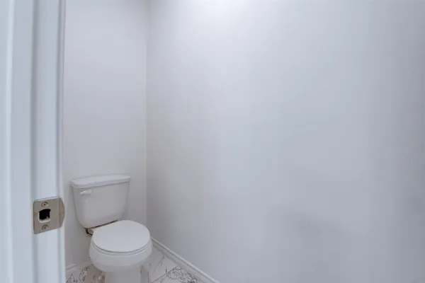 a white toilet sitting next to a white wall