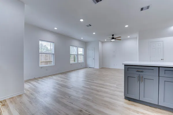 a view of an empty room with a window and wooden floor
