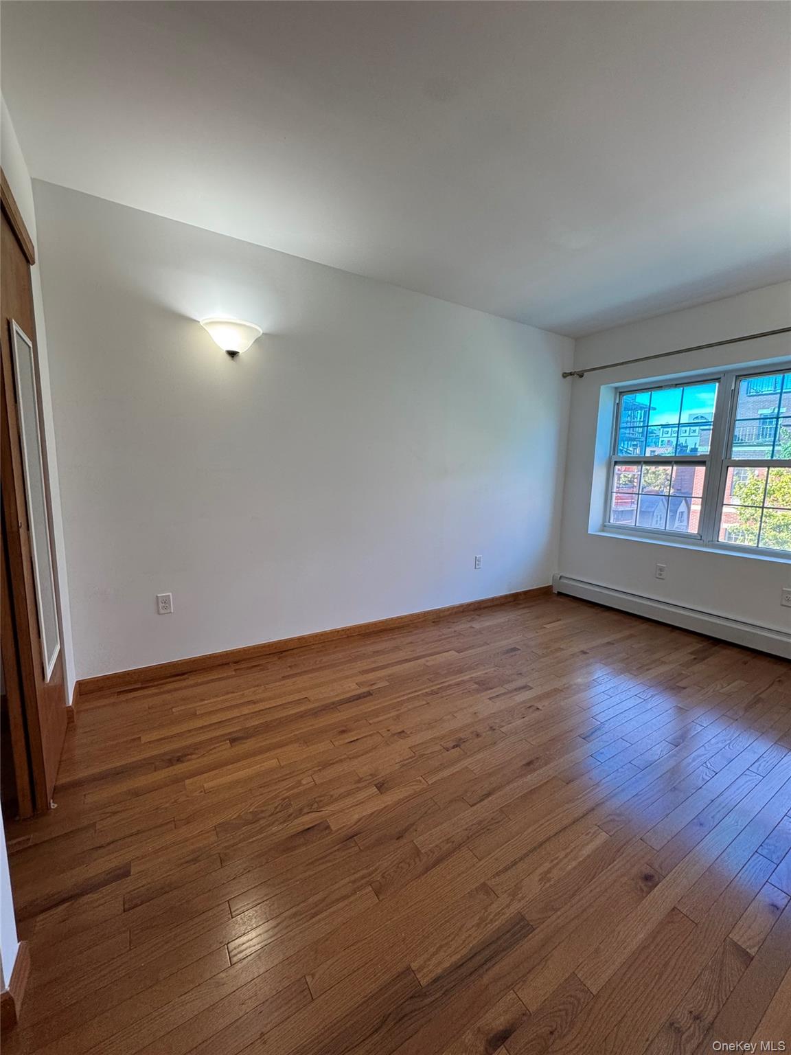35-19 Leavitt Street, Unit 3E Queens, NY 11354 - Photo 4 of 8 Empty room featuring hardwood / wood-style flooring and baseboard heating