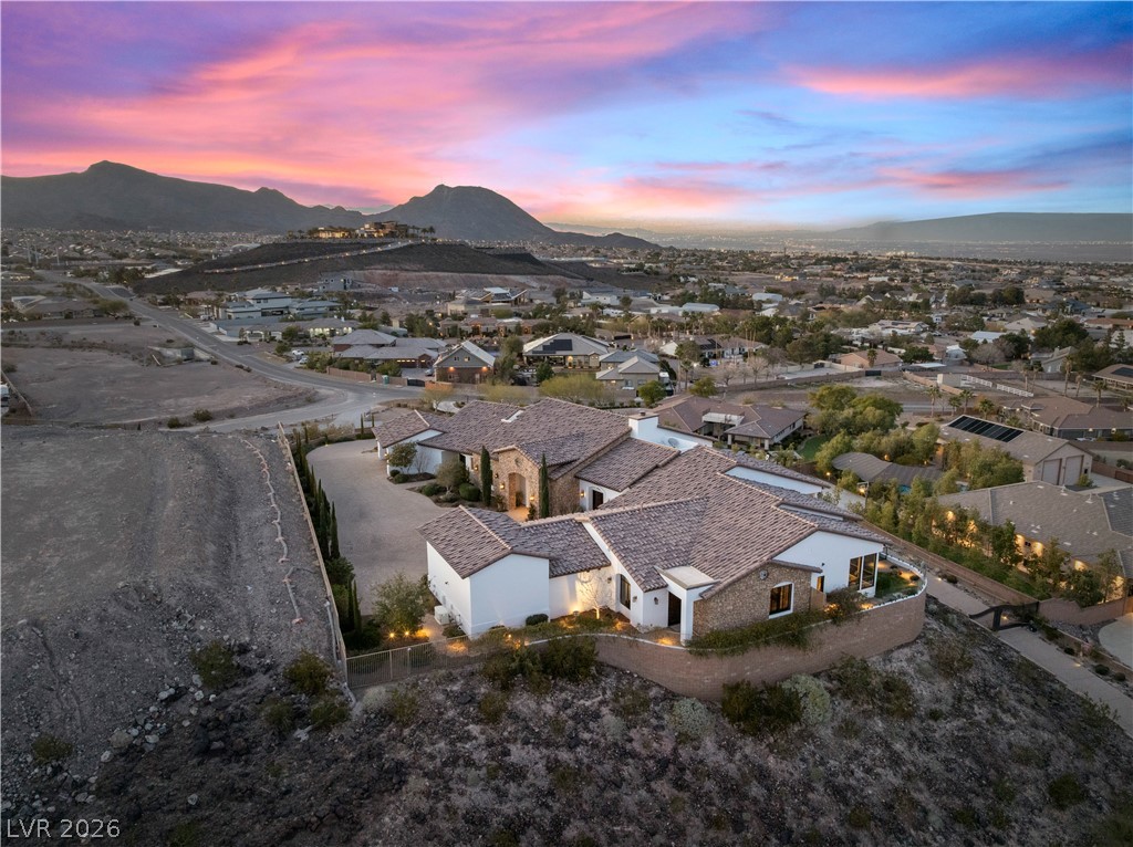 1123 Christian Road Henderson, NV 89002 - Photo 76 of 94 Dramatic sunset over mountains frames a hillside residence with a sprawling tile roof.