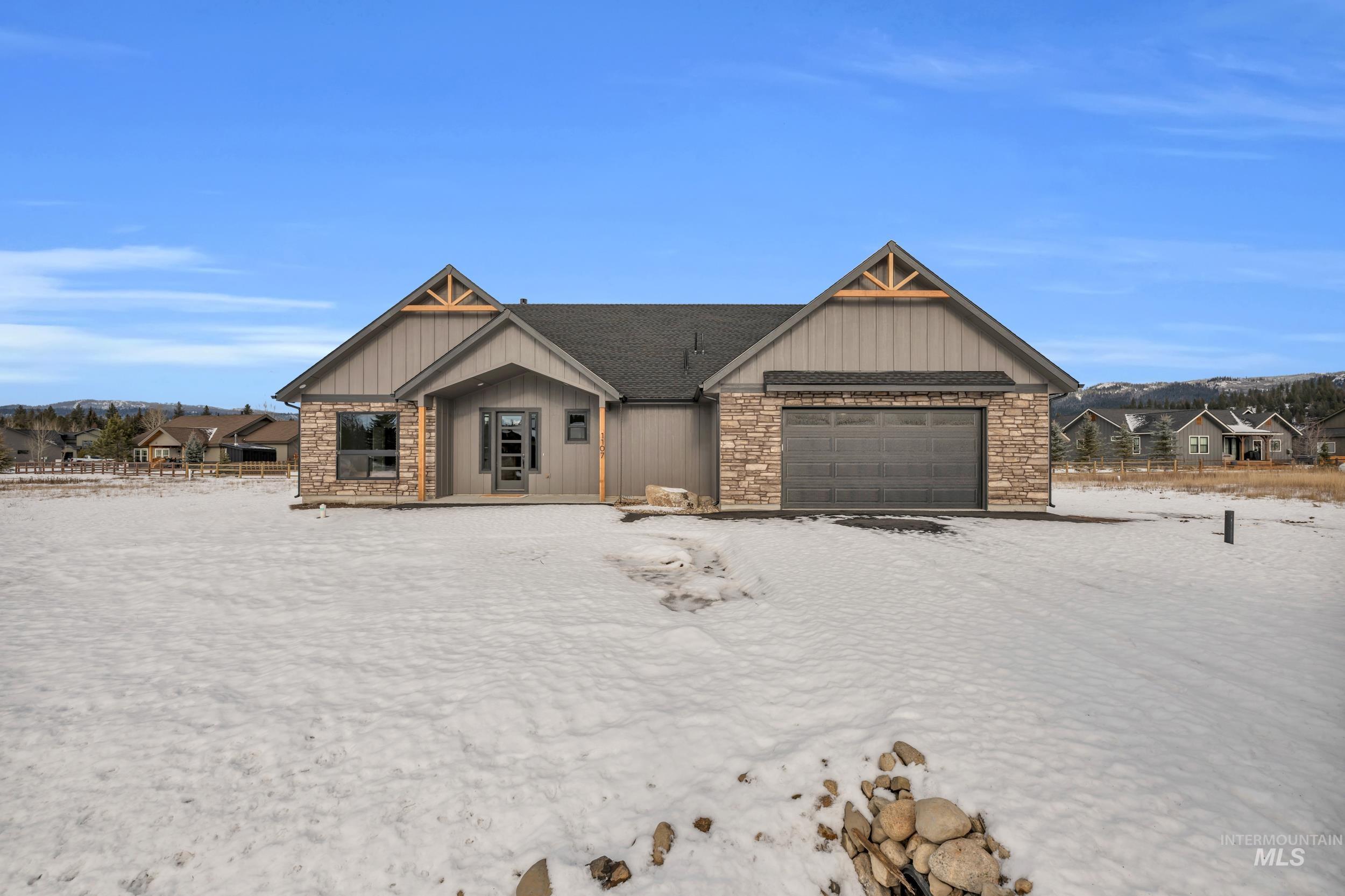 View of front of property with stone siding, an attached garage, and board and batten siding