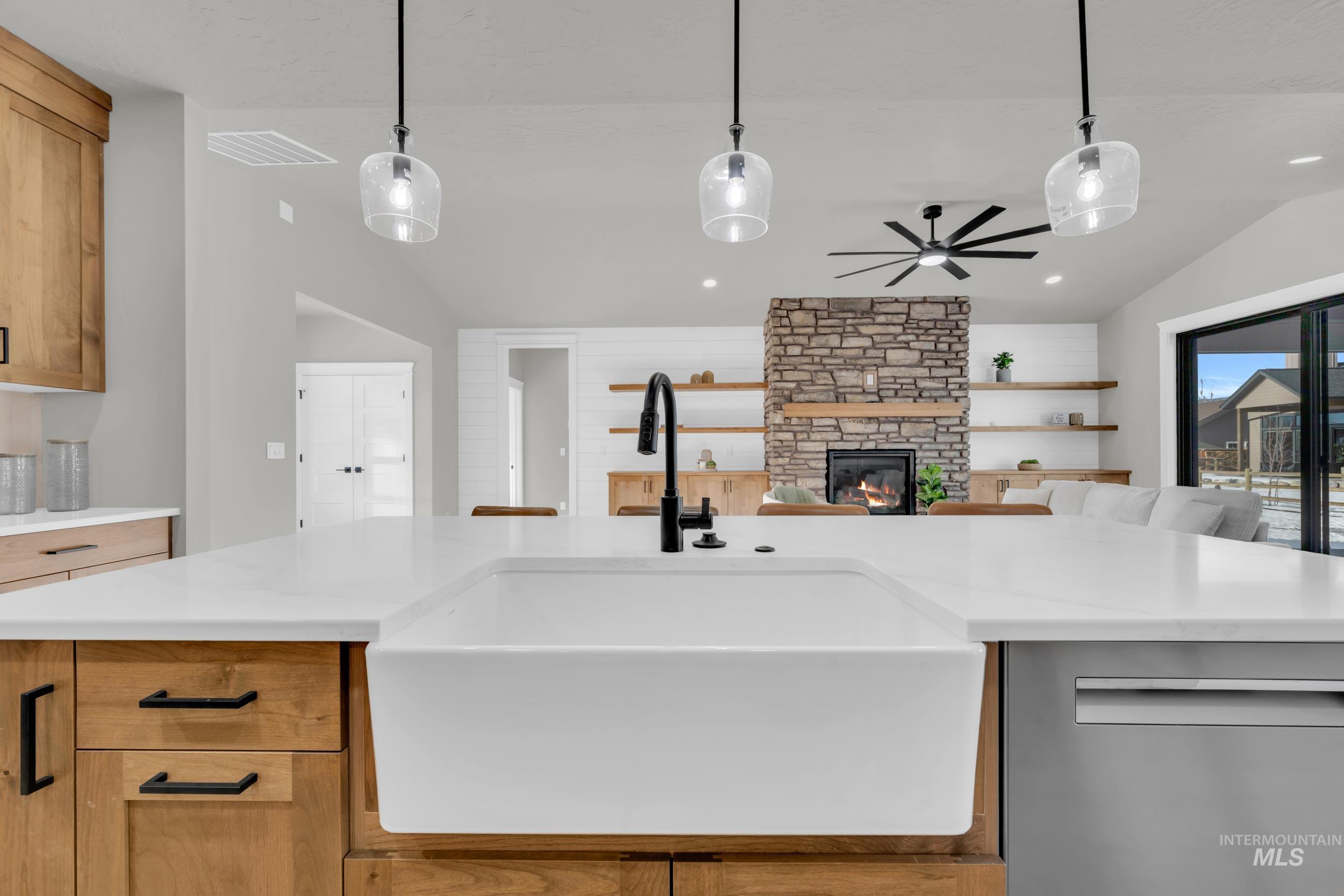1107 Mo's Way McCall, ID 83638 - Photo 19 of 50 Kitchen with lofted ceiling, dishwasher, pendant lighting, a stone fireplace, and brown cabinetry
