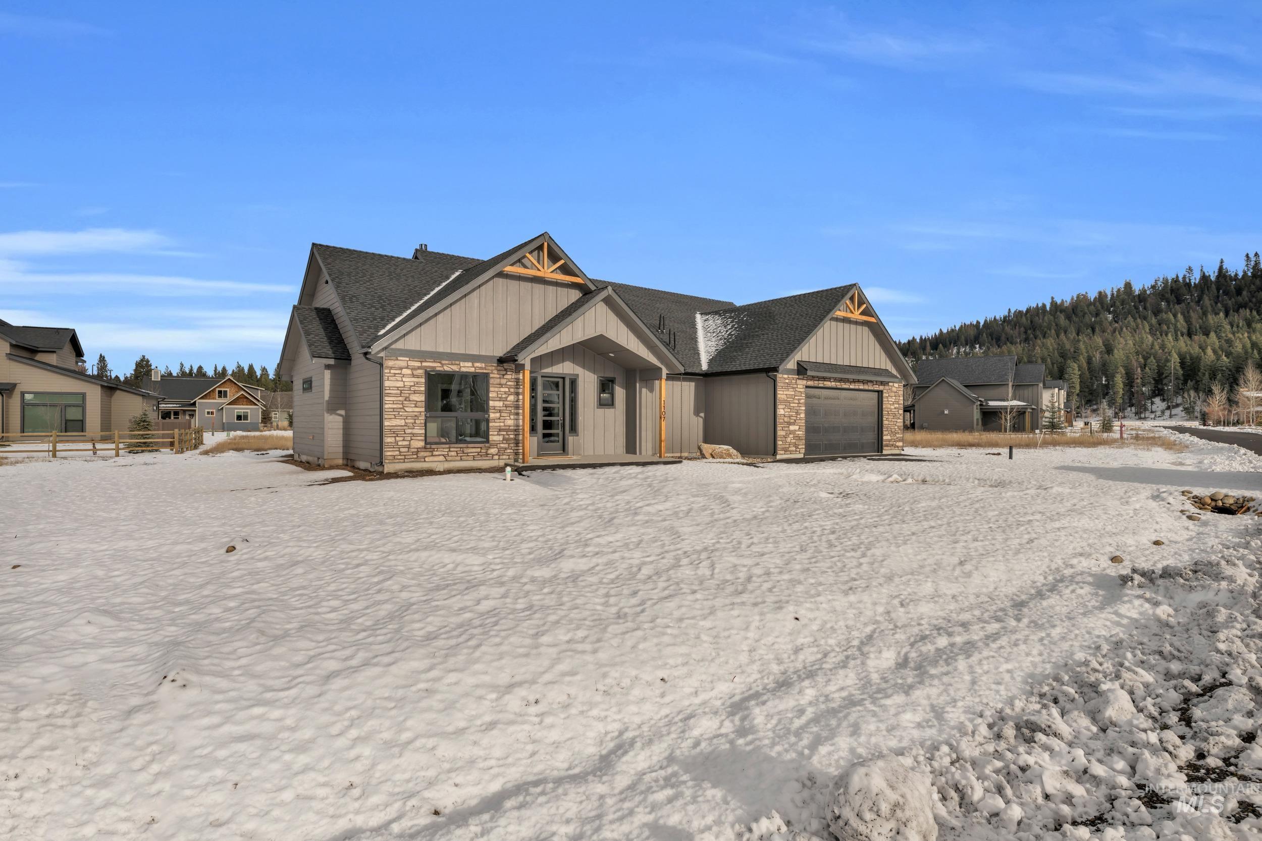 1107 Mo's Way McCall, ID 83638 - Photo 4 of 50 View of front of home featuring board and batten siding, an attached garage, stone siding, and covered porch