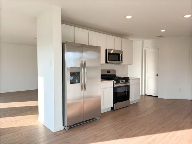 a kitchen with a refrigerator stove and wooden floor